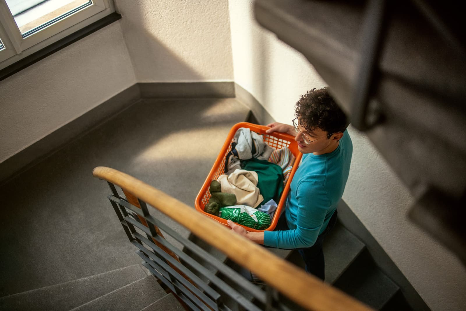 Un ragazzo con un cesto pieno di biancheria sale le scale.